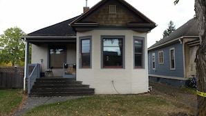 A two-story house with a front porch, a visible mailbox, and a staircase leading to the entrance.