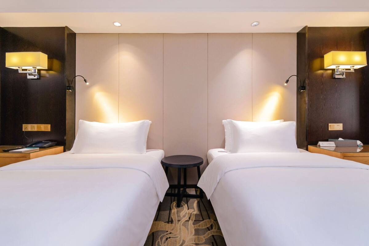 A hotel room with two beds, a small round table, and two bedside lamps.