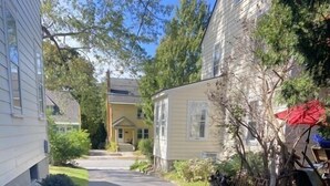 Une rue résidentielle étroite, bordée de maisons des deux côtés, un ciel dégagé et une citrouille par terre.