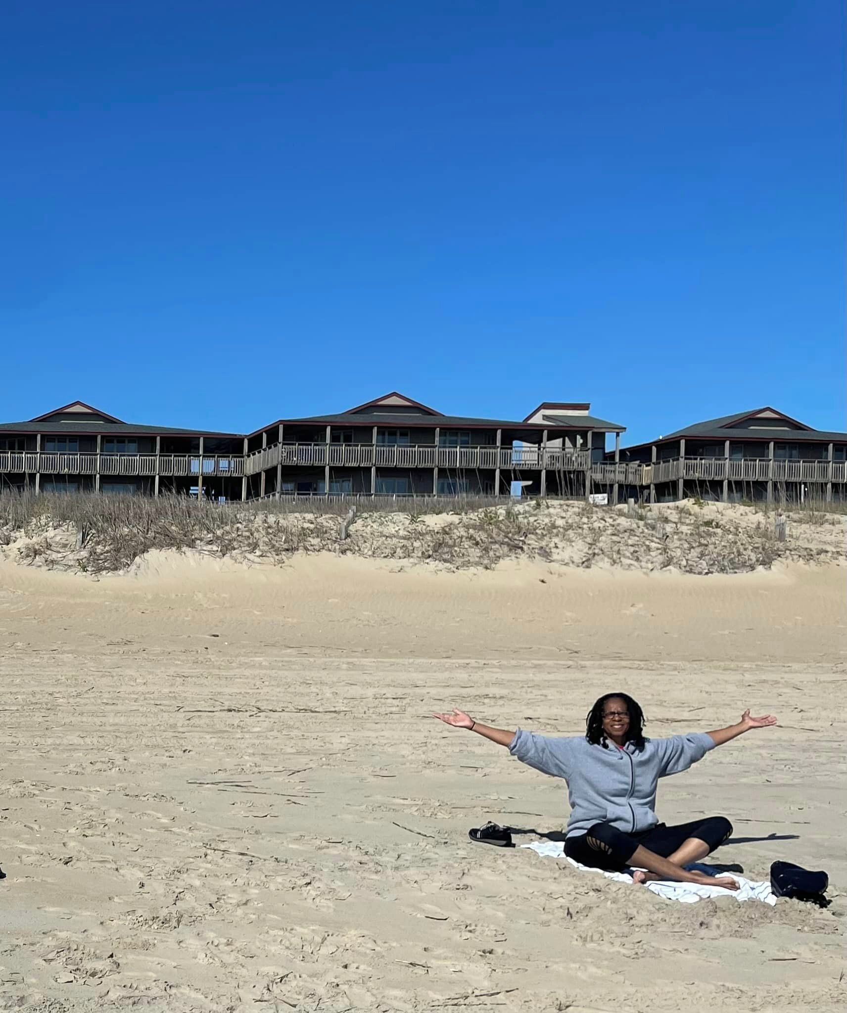 Une plage avec, en arrière-plan, un bâtiment en bois doté de plusieurs balcons.
