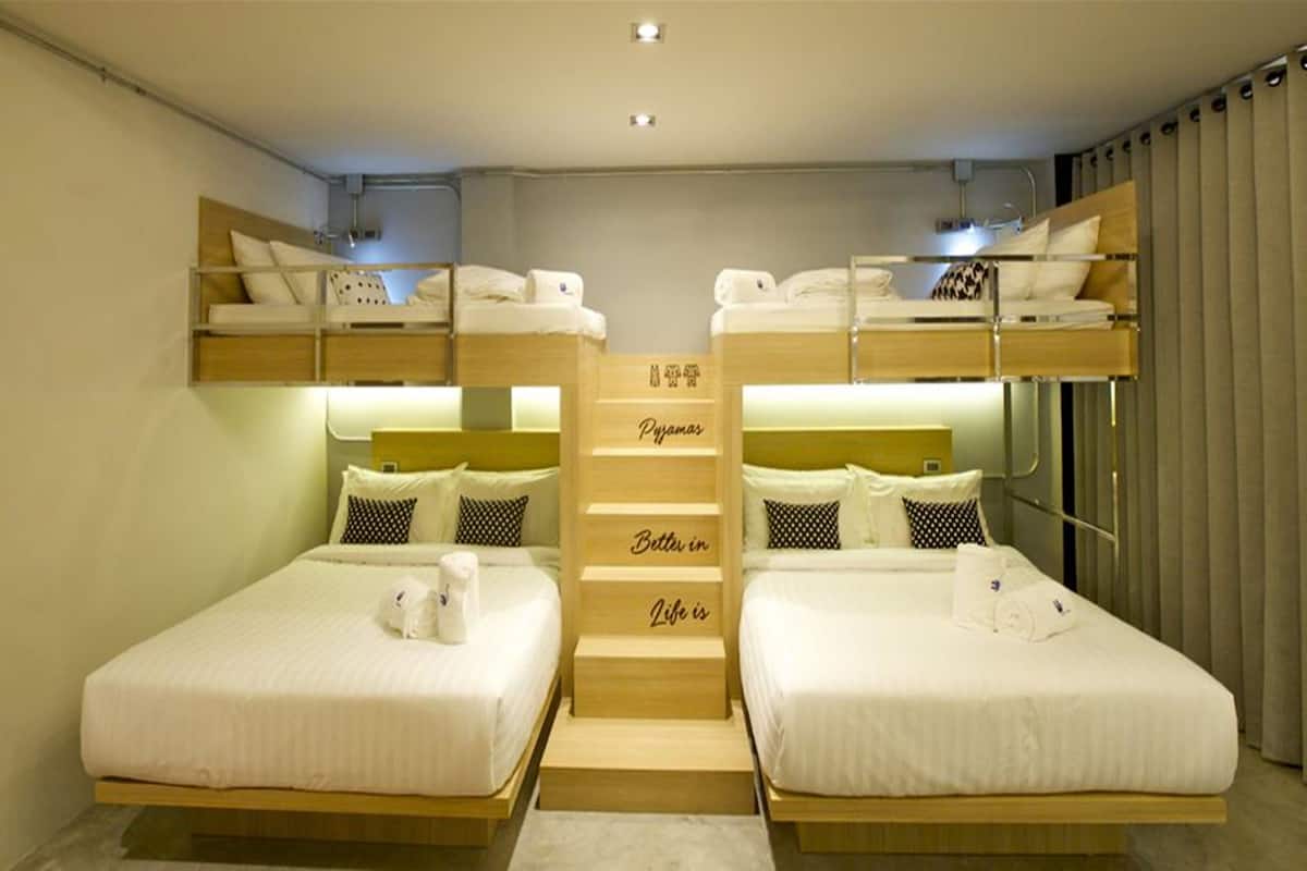 Quarto de hotel com duas camas de solteiro, escada central e beliche.