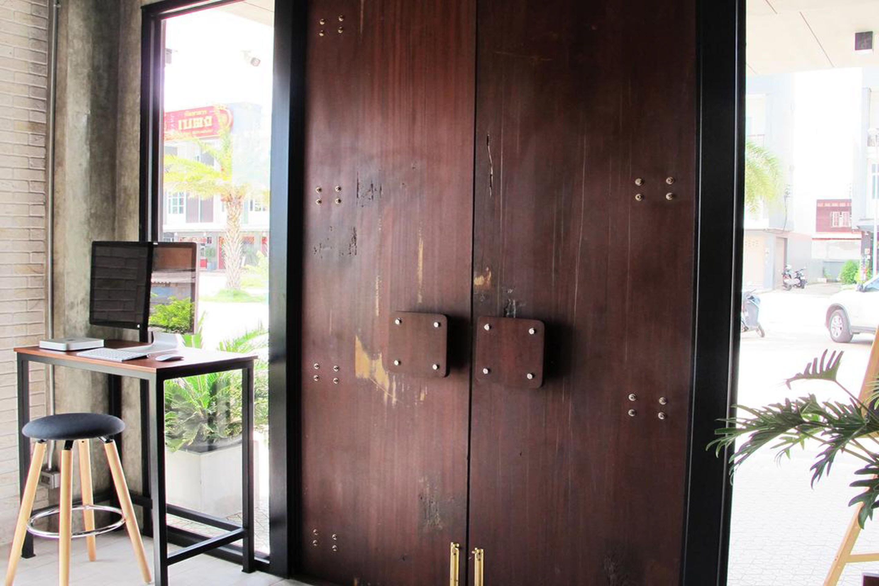 Uma porta de madeira com dobradiças de metal e uma pequena mesa com um laptop e um banquinho na frente.