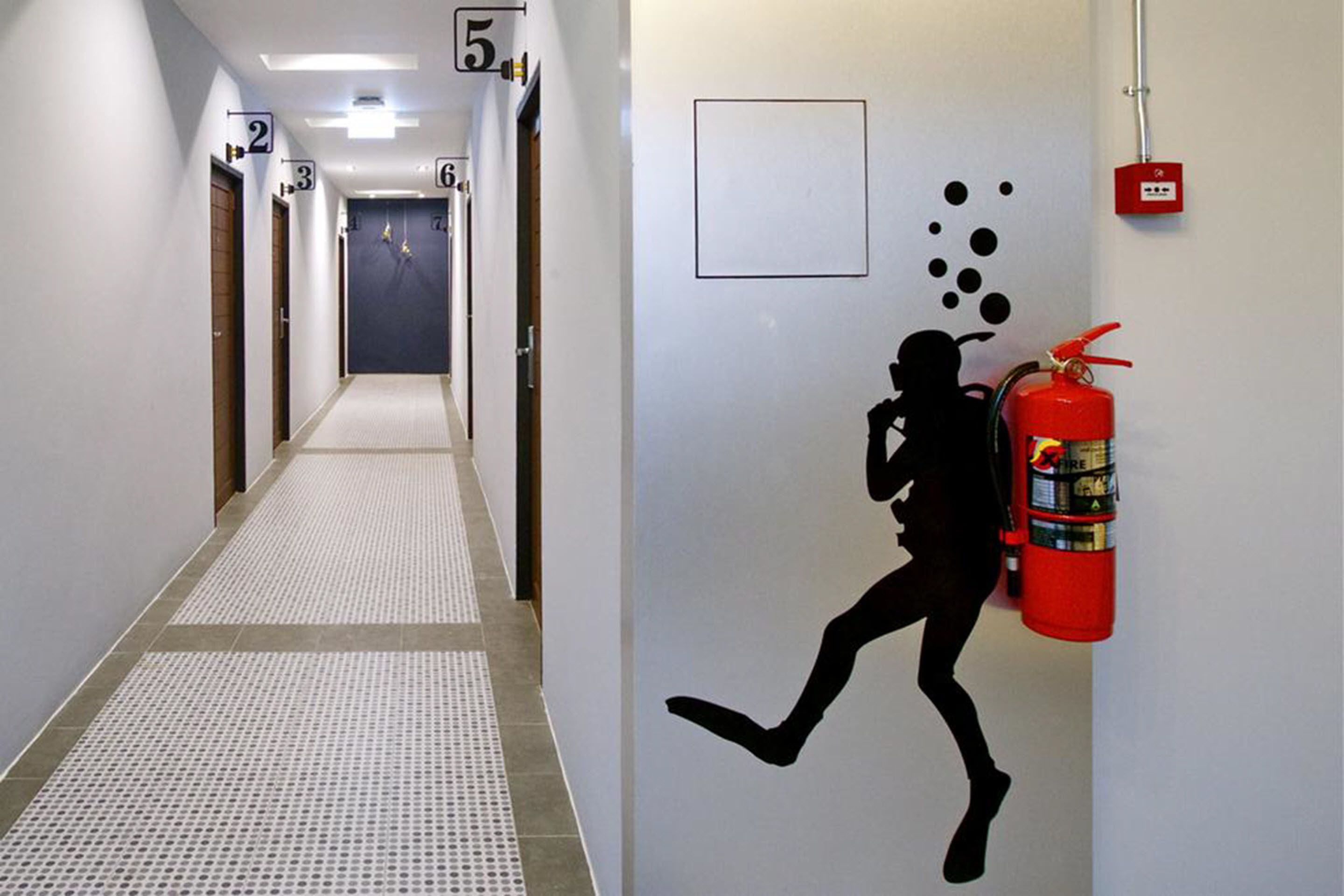 A hallway with numbered doors and a fire extinguisher mounted on the wall.