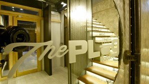 Un interior de hotel moderno con una escalera espiral, un mostrador de recepción y un letrero grande que dice "The PL".