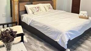 A modern bedroom with a large bed, wooden headboard, and a bedside table with a vase of flowers. - Sainamtok Resort (Khao Kho)
