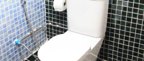 A bathroom with a white toilet, a shower, and a tiled wall.