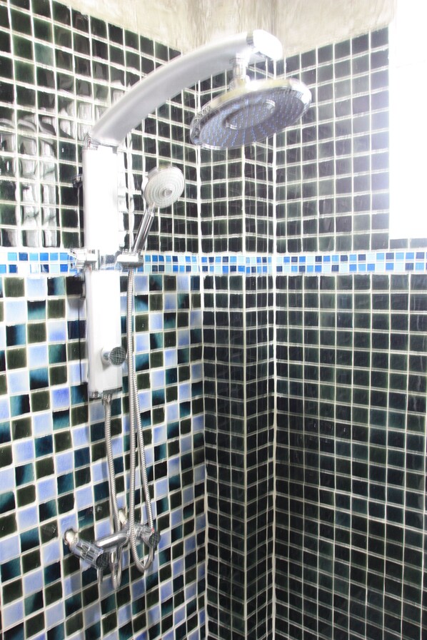 A shower with a handheld showerhead and a wall-mounted control panel.