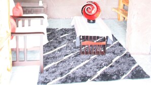 A cozy room with a stone wall, a small table with a red object, a bench, and a white chair. - Sainamtok Resort (Khao Kho)