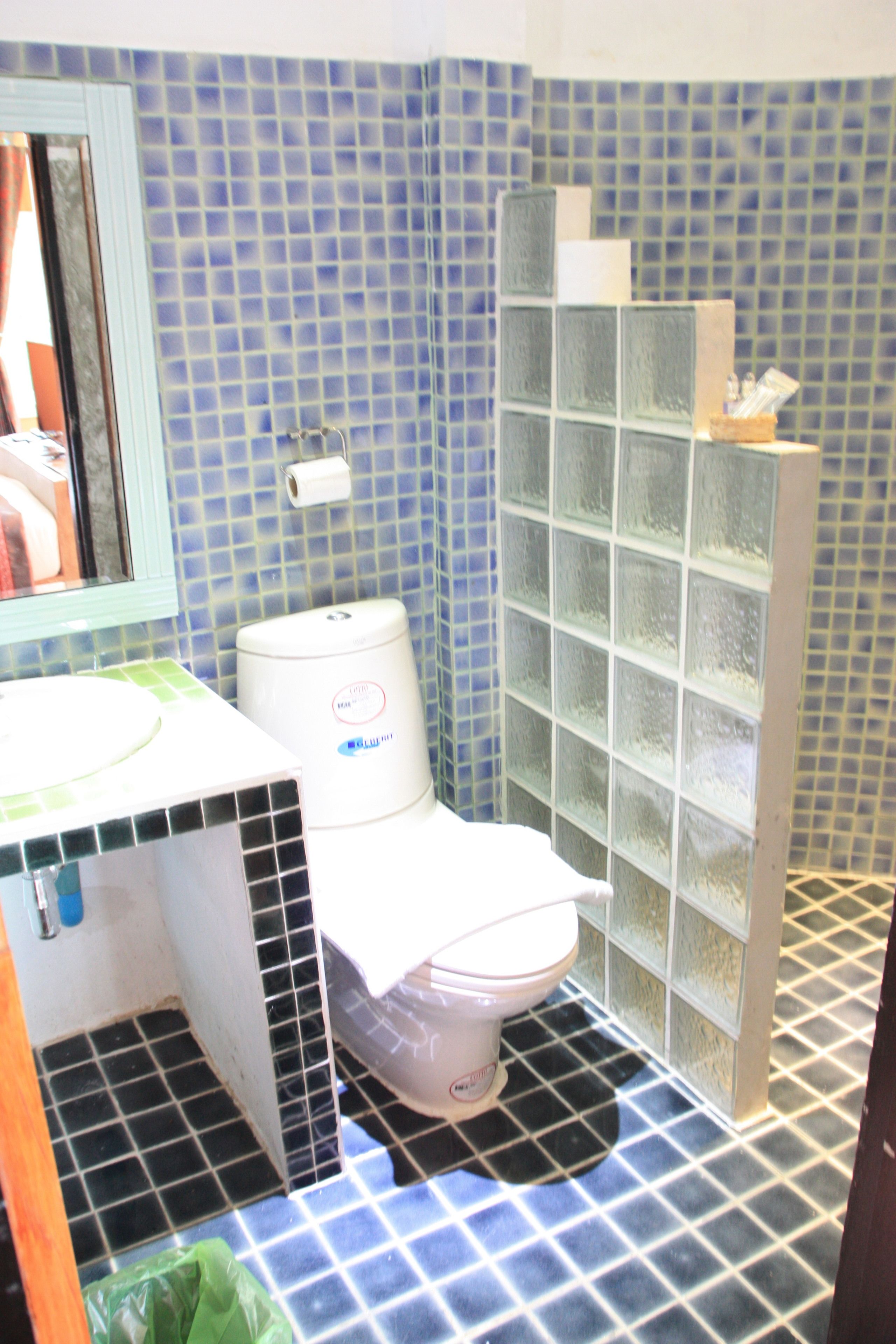 Et badeværelse med toilet, håndvask og brusekabine i glas.