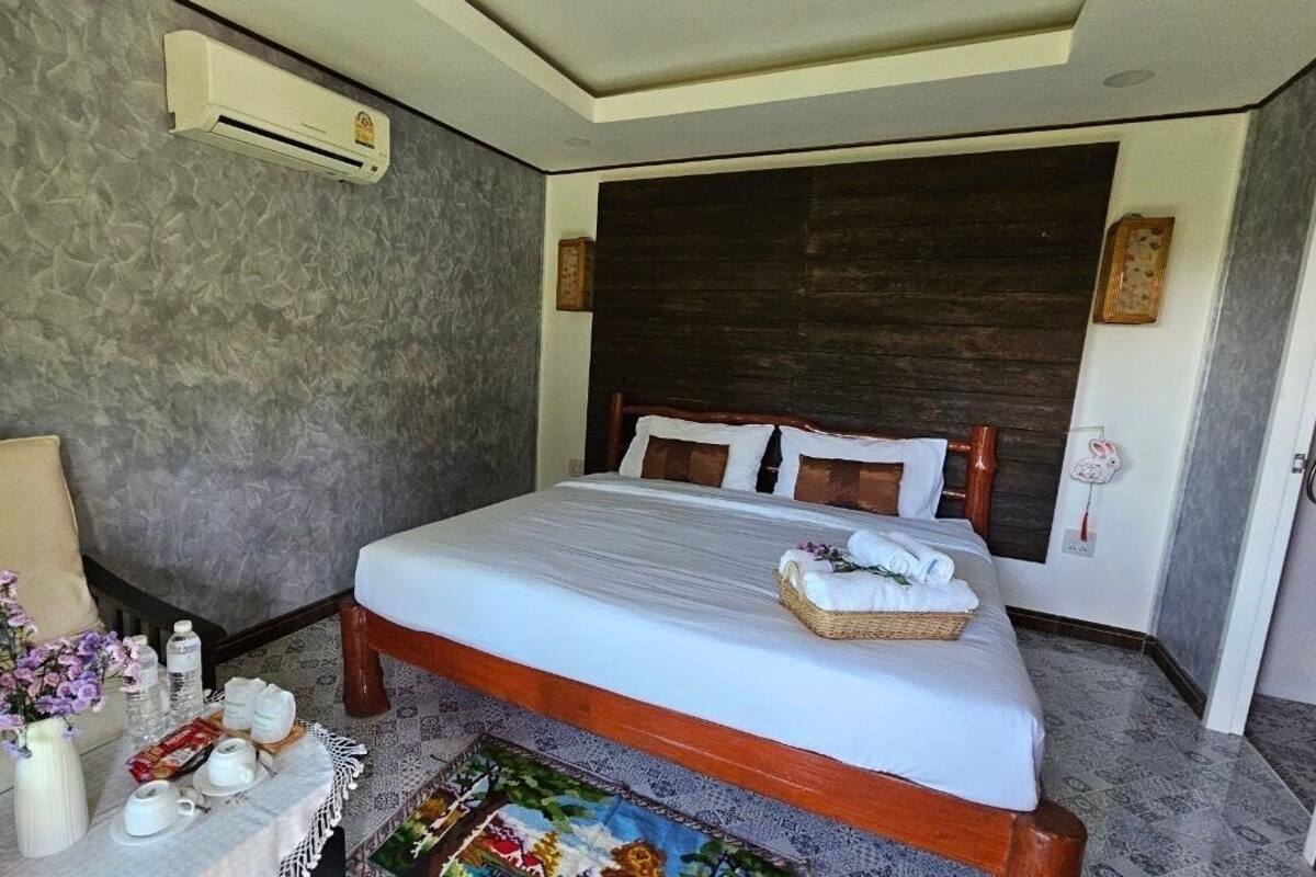 A hotel room with a bed, bedside table, and a small sitting area with a sofa and a vase of flowers.