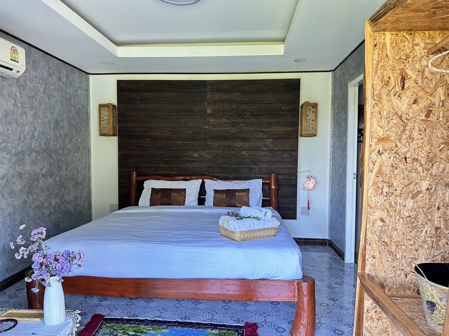 A bedroom with a wooden bed, a nightstand with a lamp, and a decorative vase.