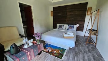 A bedroom with a bed, bedside table, and a small table with a vase and towels.