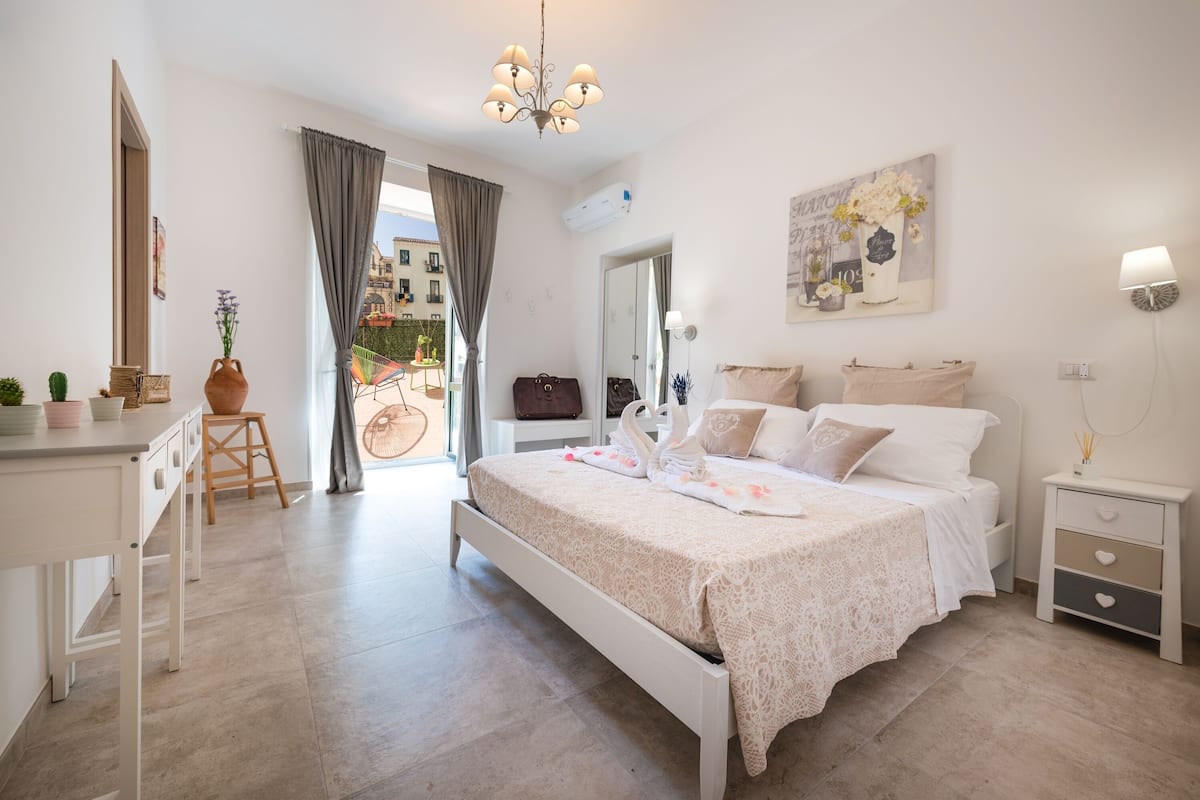 Un dormitorio con cama, mesita de noche y vistas al exterior.