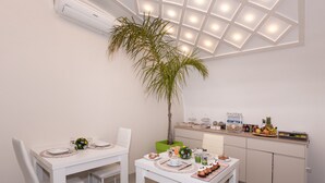 Una cocina moderna con armarios blancos, un comedor con sillas blancas e iluminación empotrada en el techo.