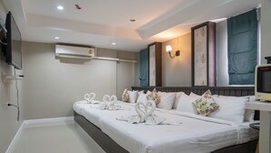 Una habitación de hotel con una cama grande, aire acondicionado, televisor montado en la pared y almohadas decorativas.