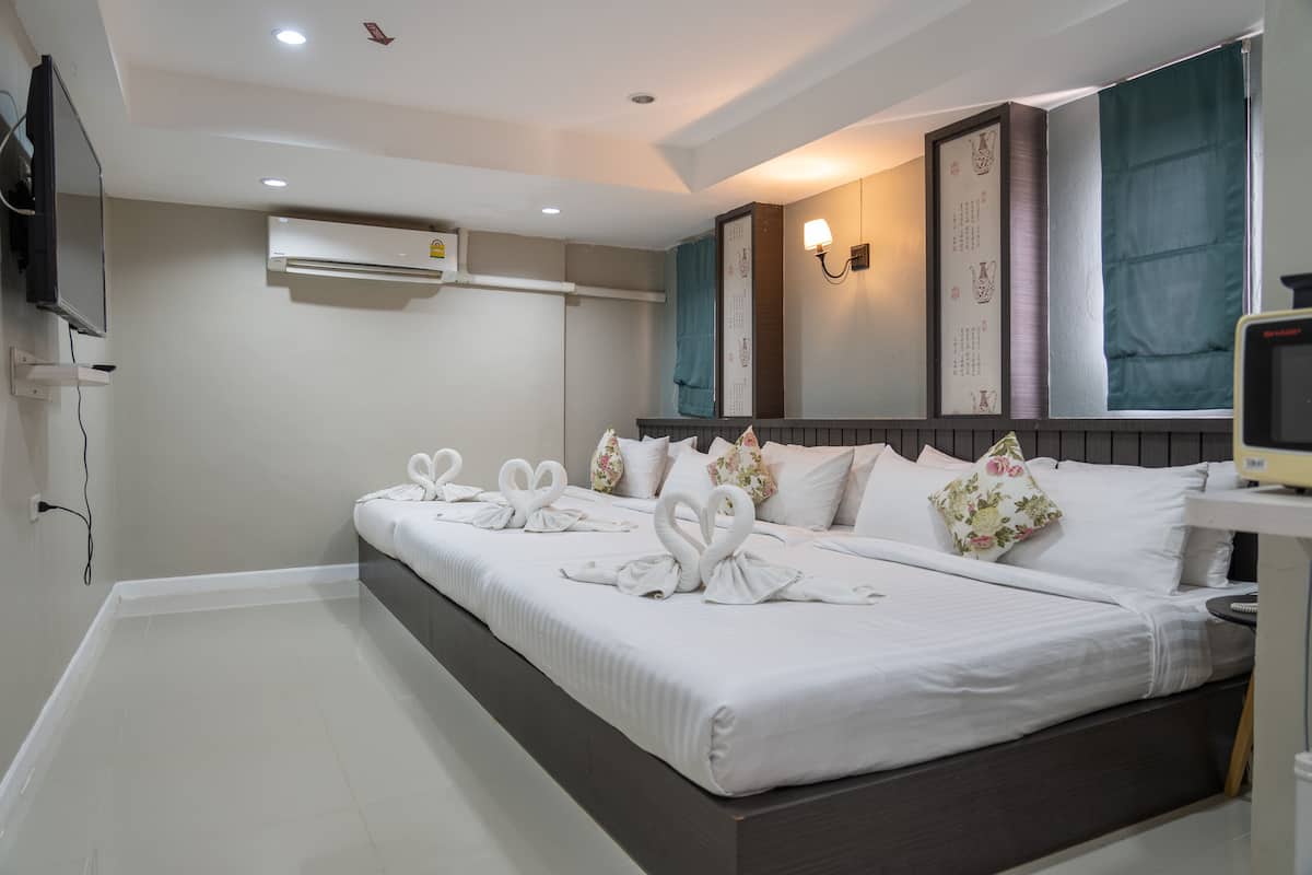 Une chambre d’hôtel dotée d’un grand lit, de la climatisation, d’un téléviseur fixé au mur et de coussins décoratifs.