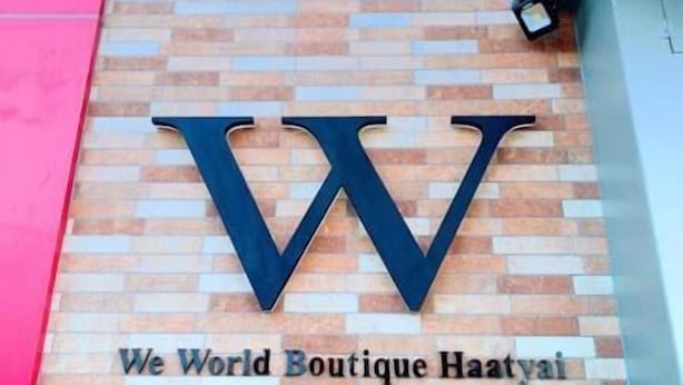 Un letrero con el logotipo y el nombre 'We World Boutique Haayai' en una pared de ladrillo.