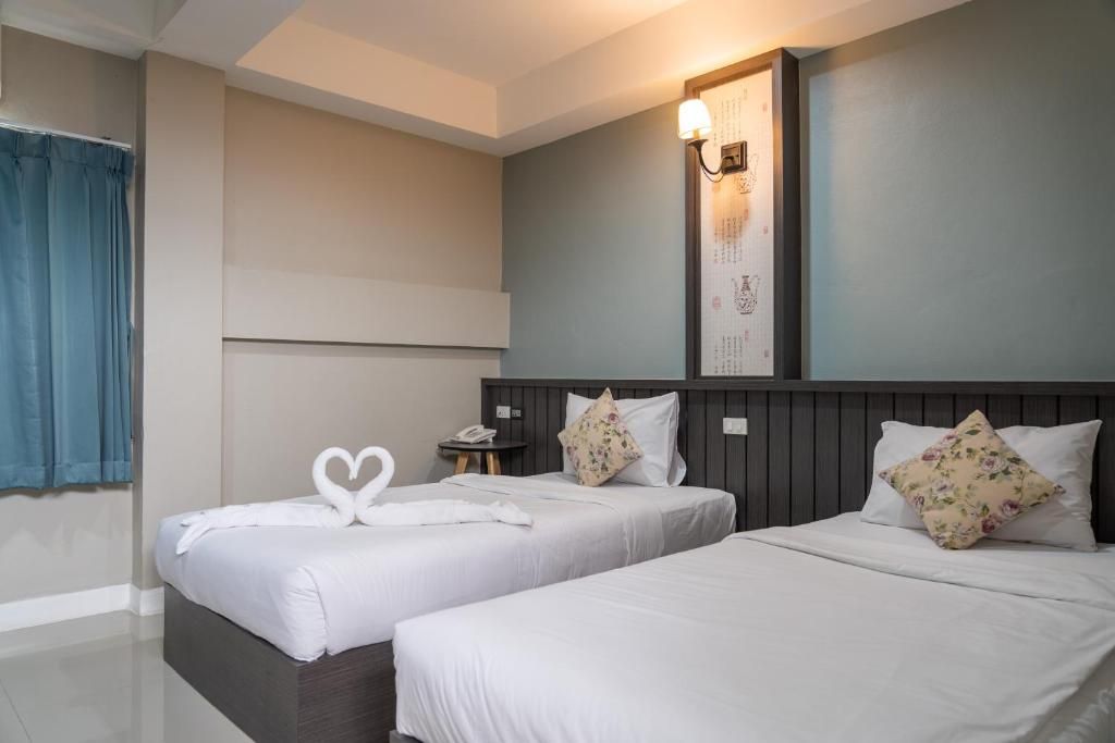A hotel room with two beds, a nightstand, a wall-mounted light, and a curtain.