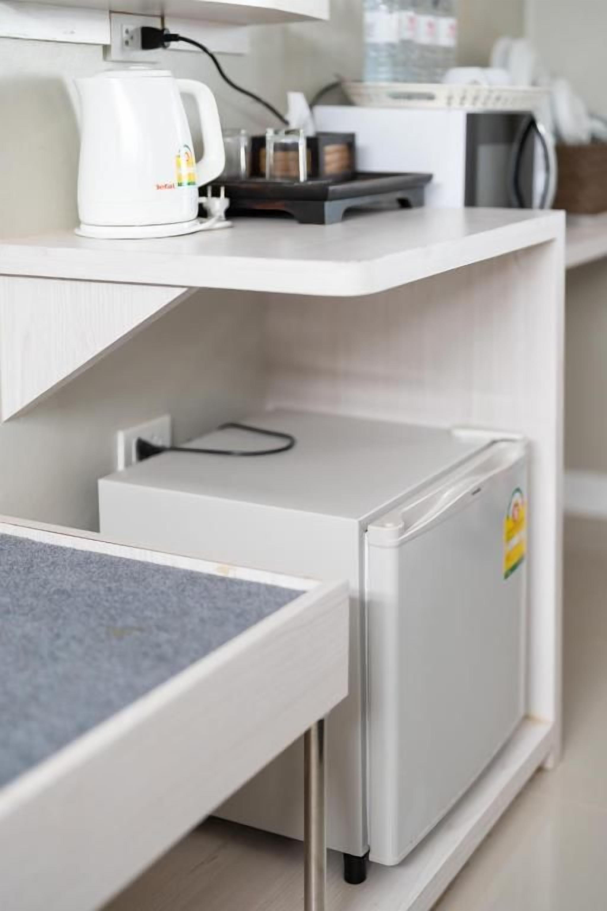 A compact kitchenette with a coffee maker, a small refrigerator, and a microwave on a white countertop.