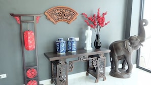 Una habitación con una consola de madera oscura, un abanico decorativo, jarrones y una estatua de elefante.