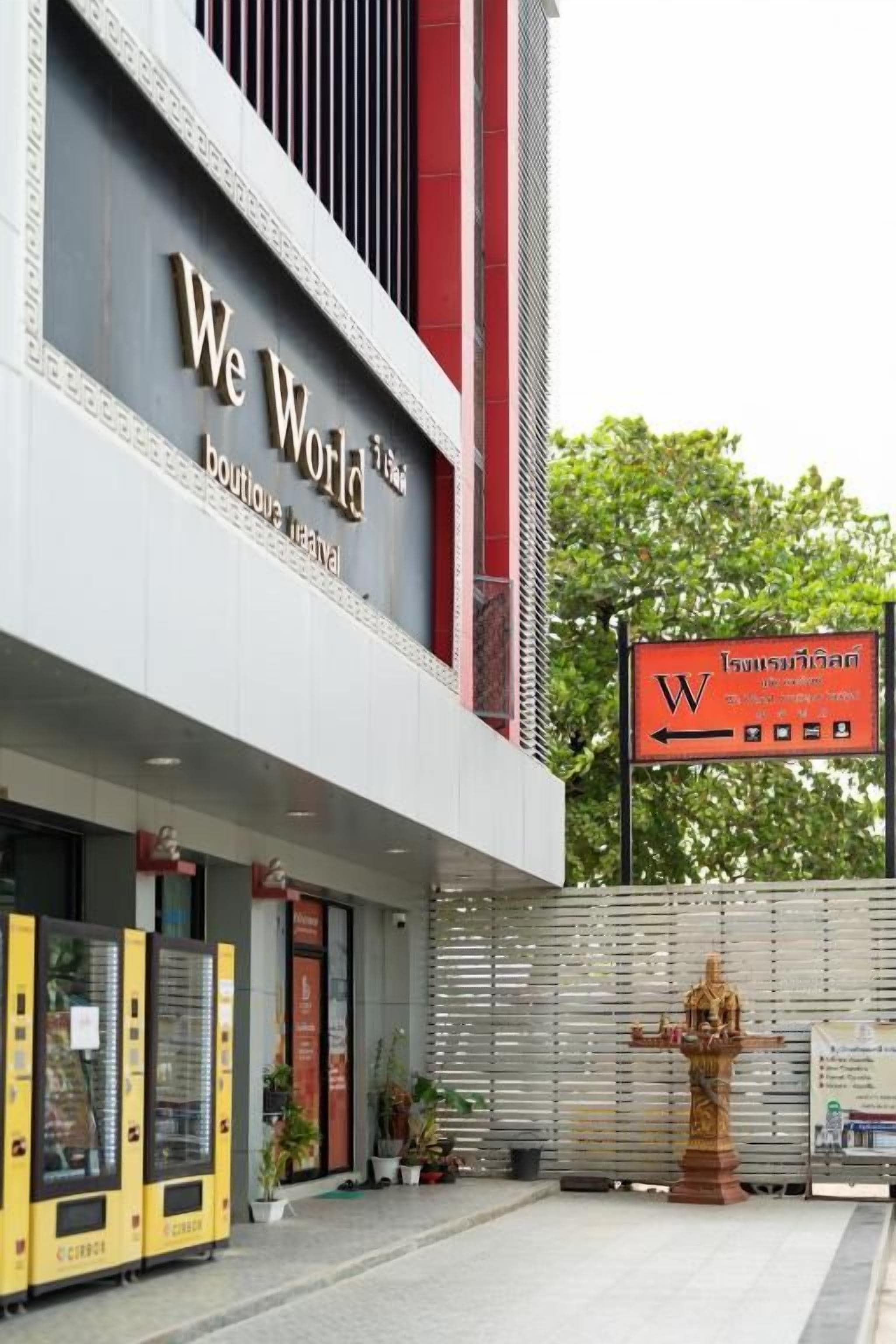 Un edificio con un letrero que dice 'We World Boutique Festival' y una señalización que indica dirección a la derecha.