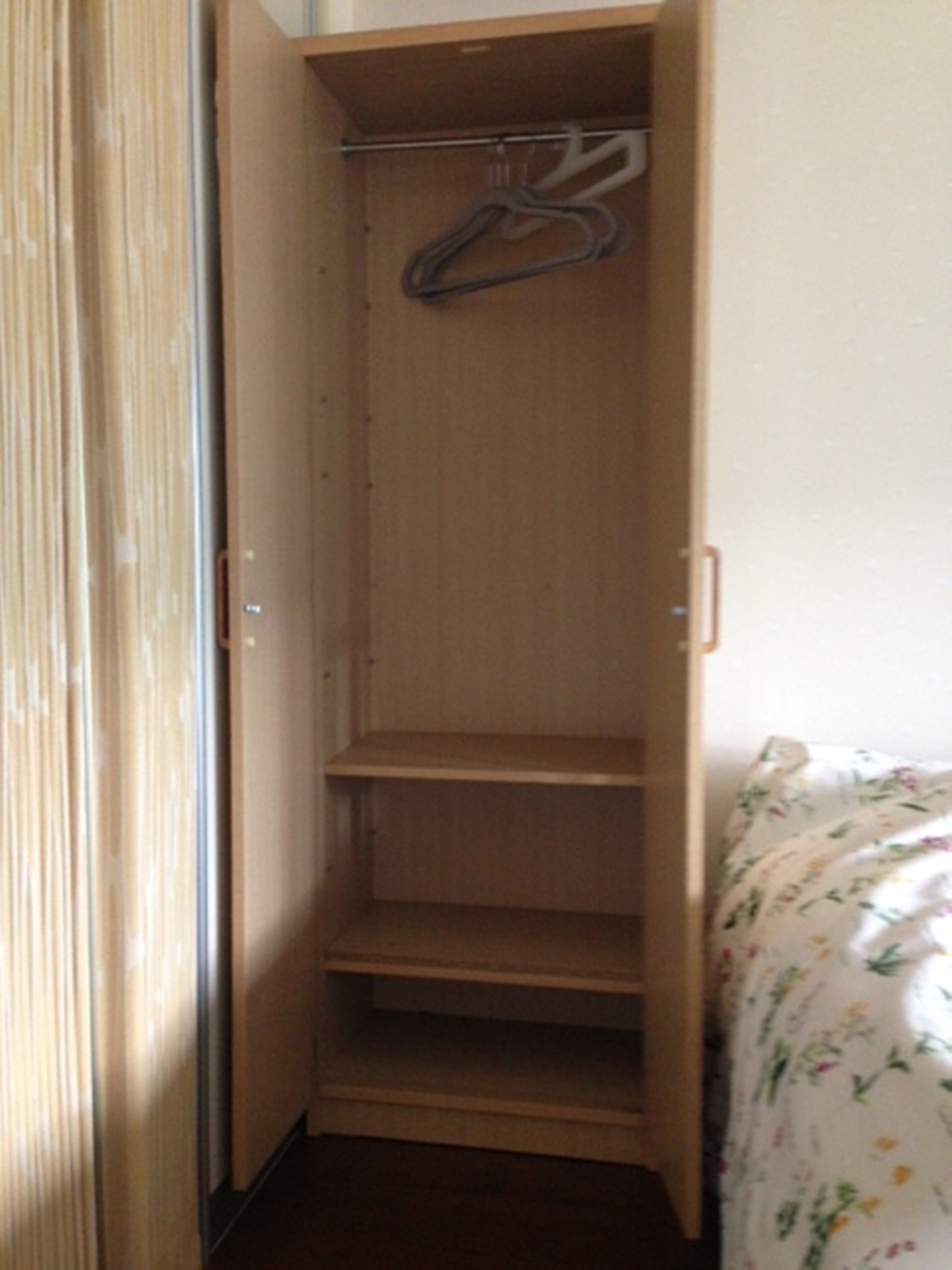A wooden wardrobe with a hanging rod and multiple shelves.