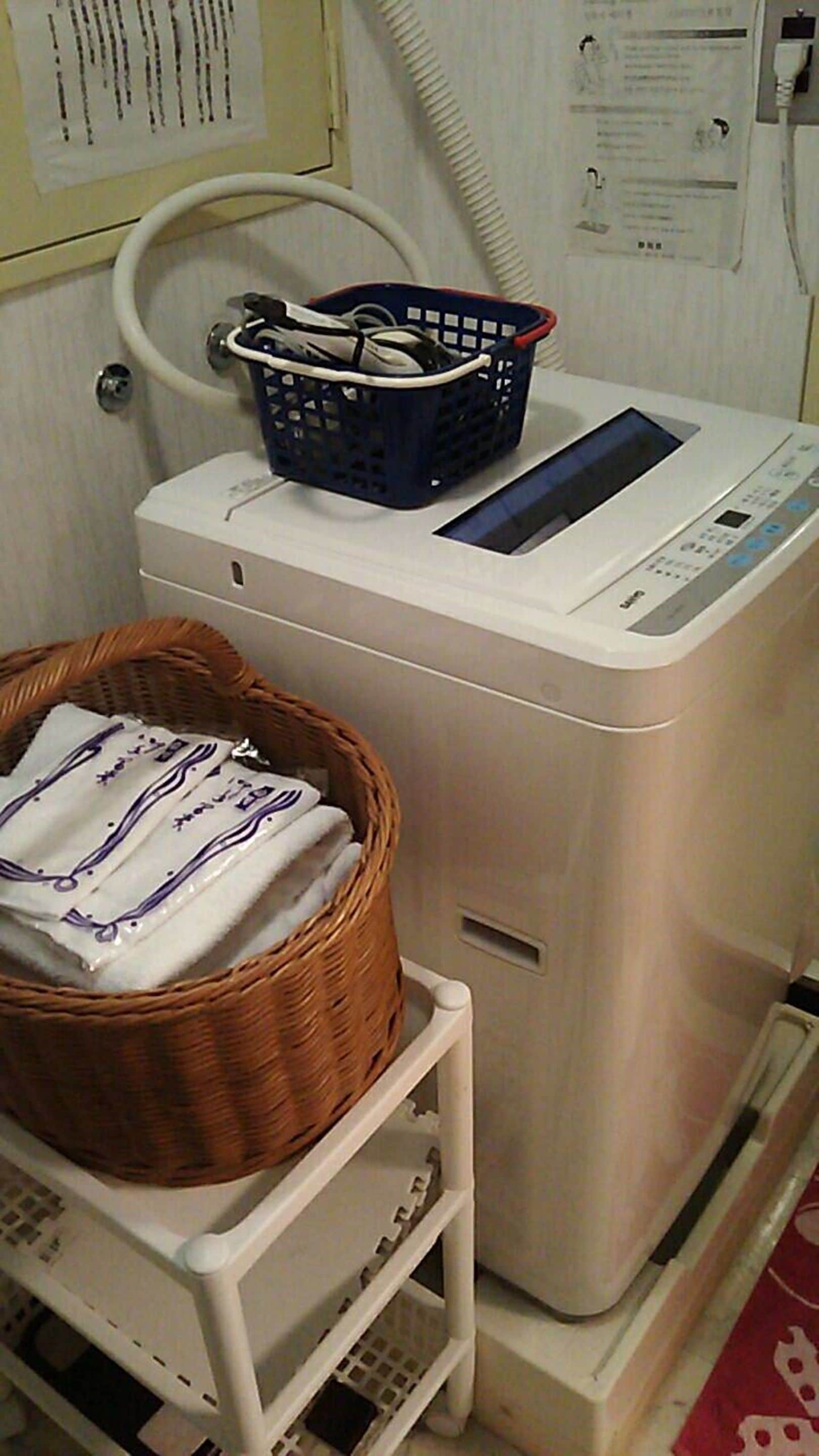A laundry machine with a basket of folded clothes on a cart.