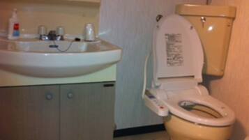 A bathroom with a toilet, sink, and cabinet.
