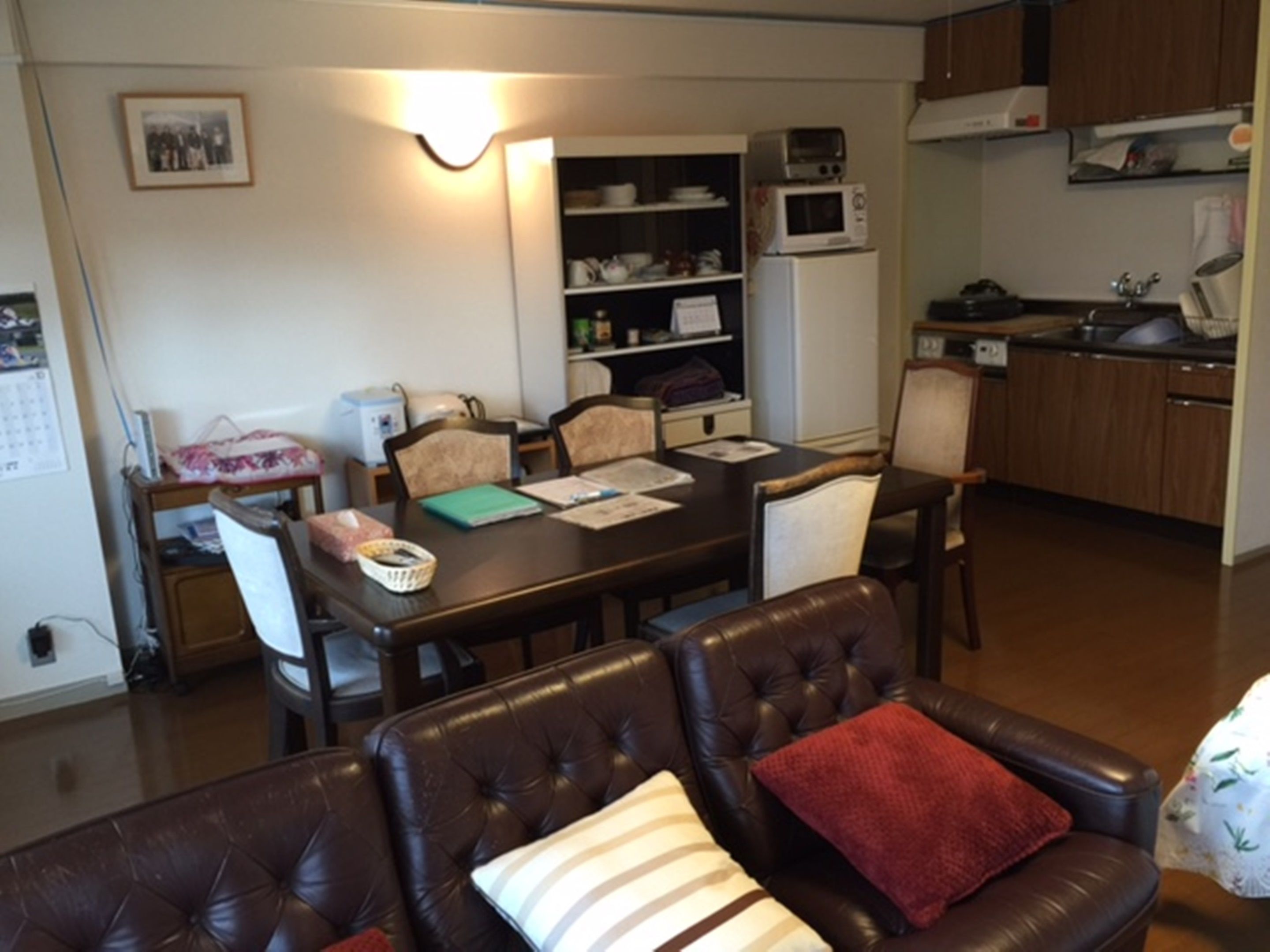 Un espacio habitable compacto con mesa de comedor, sofá de cuero y kitchenette.