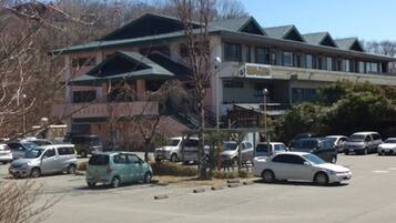A parking lot with several cars, a building with a green roof, and a sign that reads "RESTAURANT".