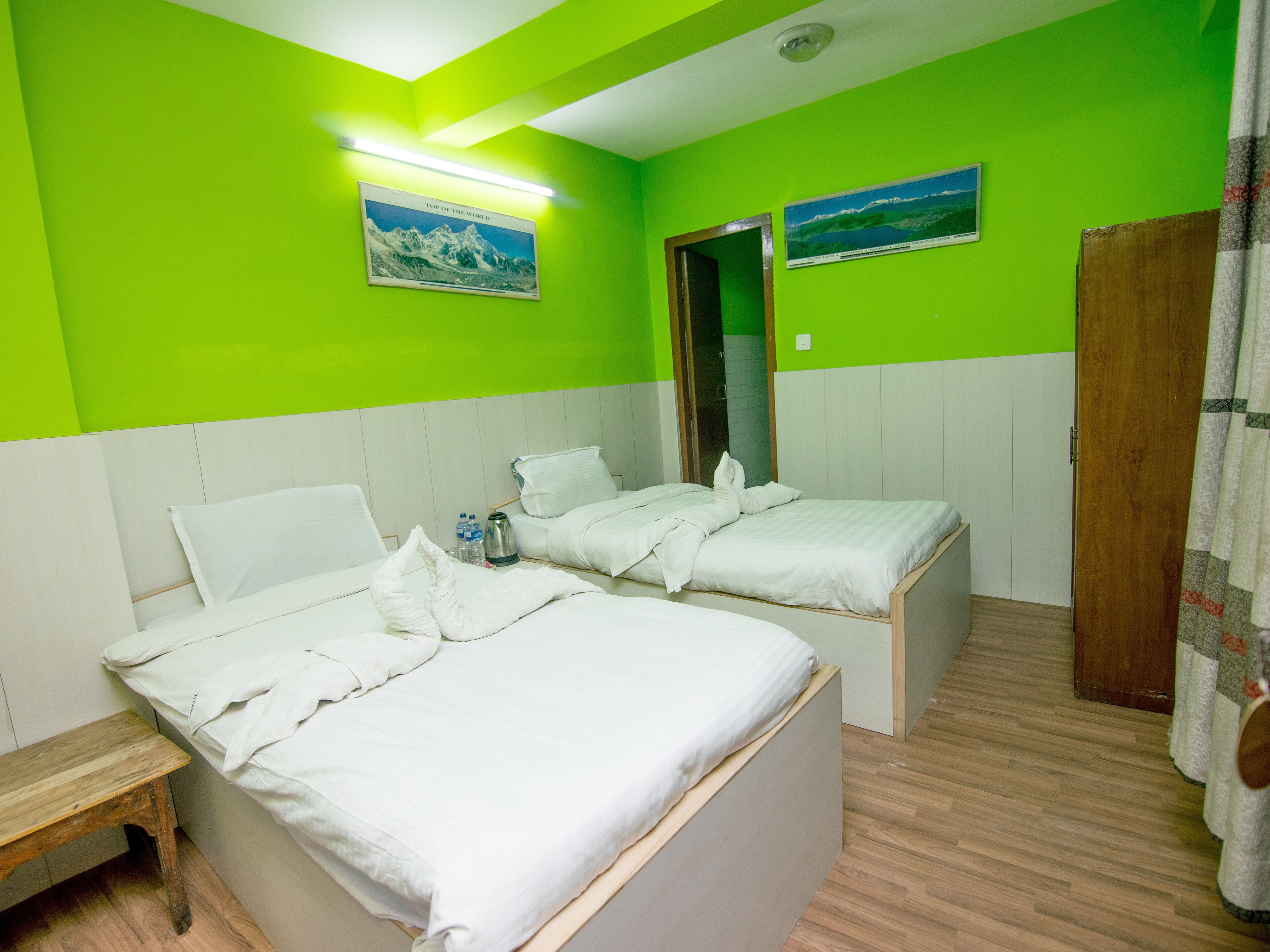 A room with two beds, a wooden bench, and a door.