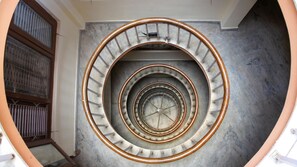 A spiral staircase with a metal railing and a concrete wall. - Hotel Pomelo House (Kathmandu)