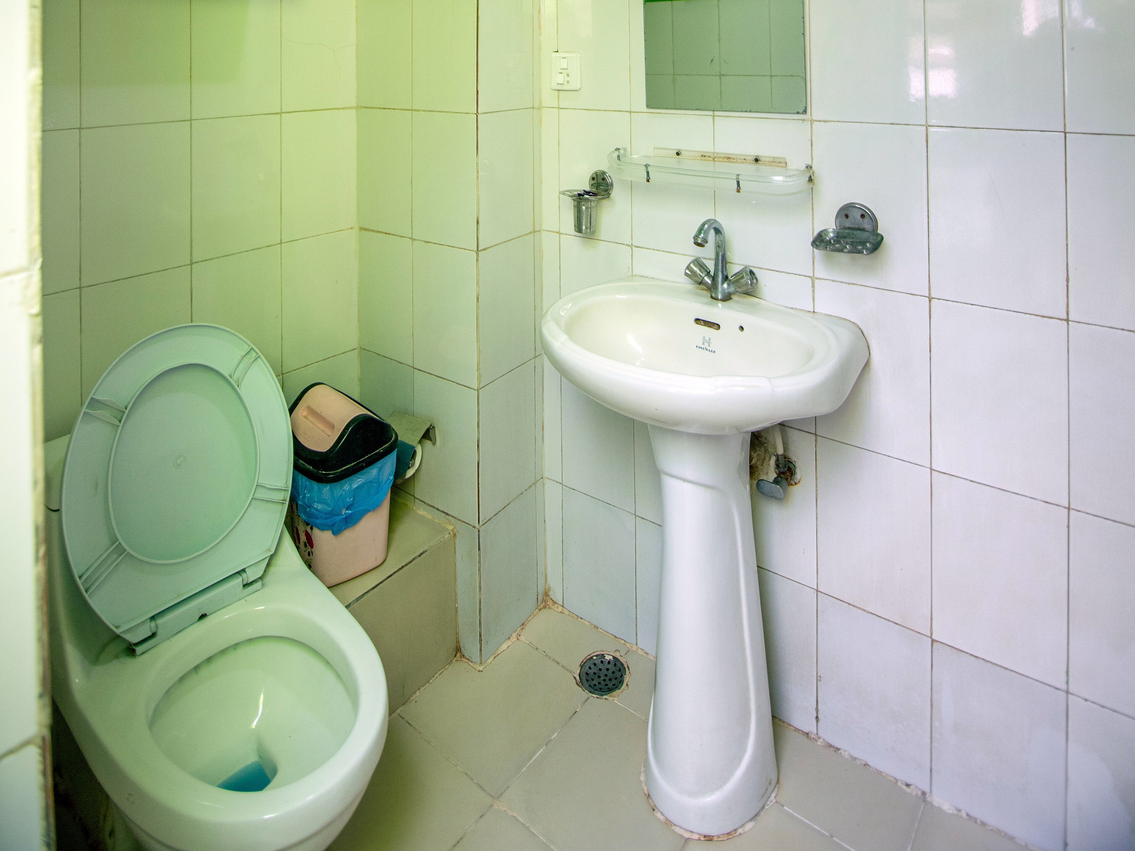A bathroom with a toilet, sink, and a mirror.
