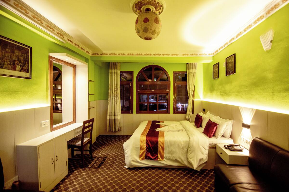 Une chambre d’hôtel avec un lit, un bureau, une chaise et une fenêtre avec des rideaux.