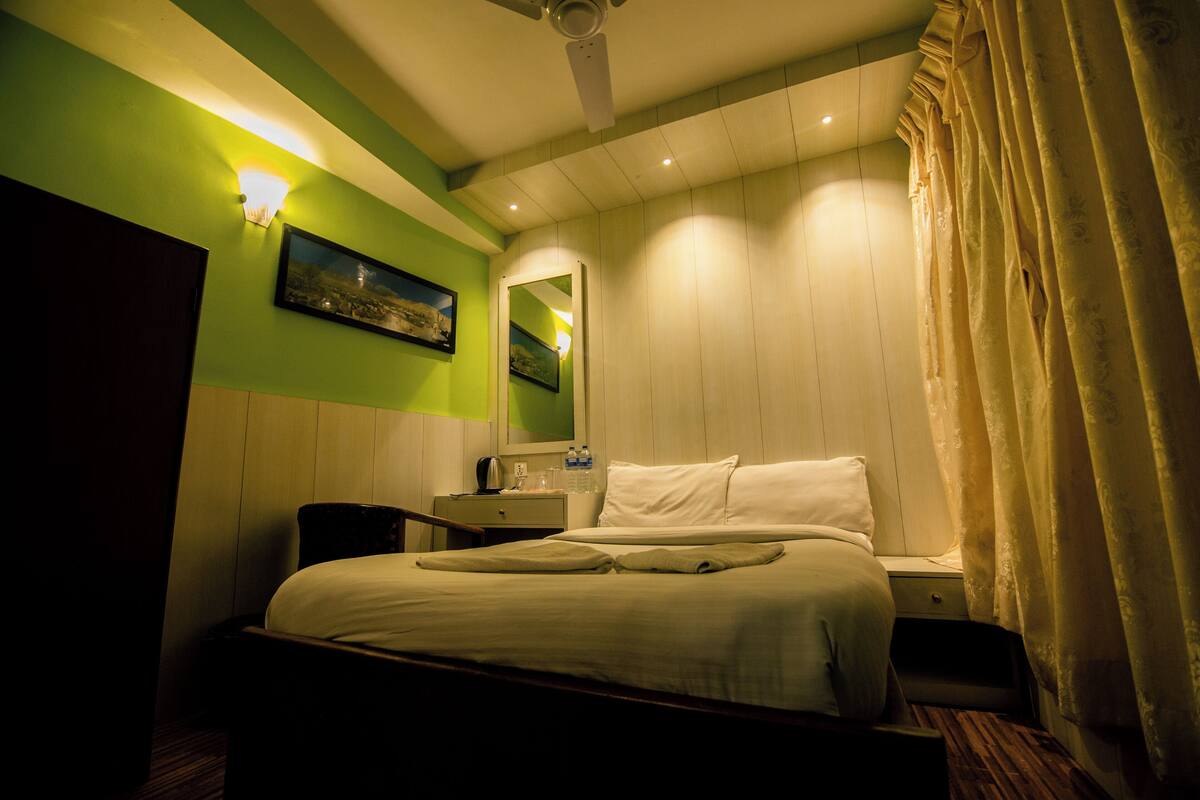 Une chambre d’hôtel avec un lit, une table de chevet, une lampe et un miroir.