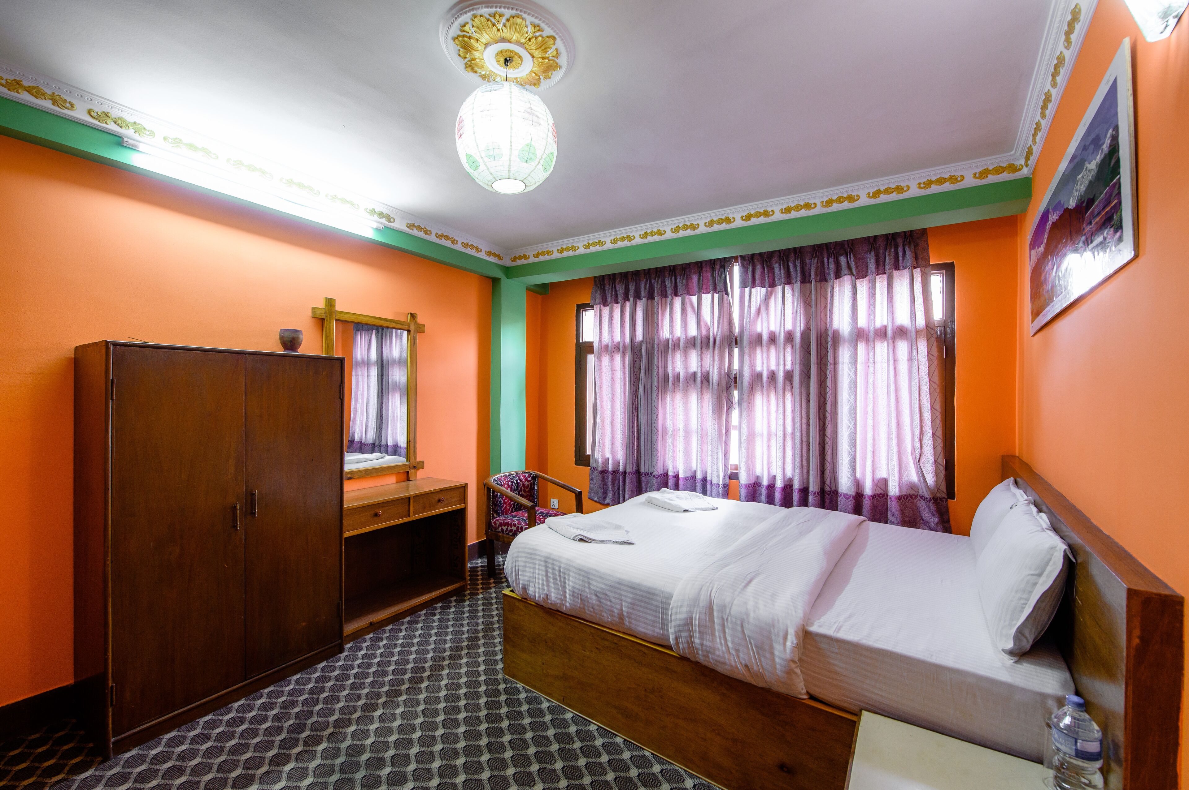 Una habitación de hotel con cama, armario, escritorio y una silla.