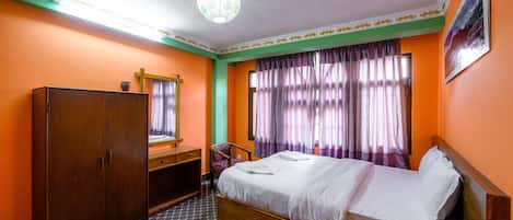 Una habitación de hotel con cama, armario, escritorio y una silla.