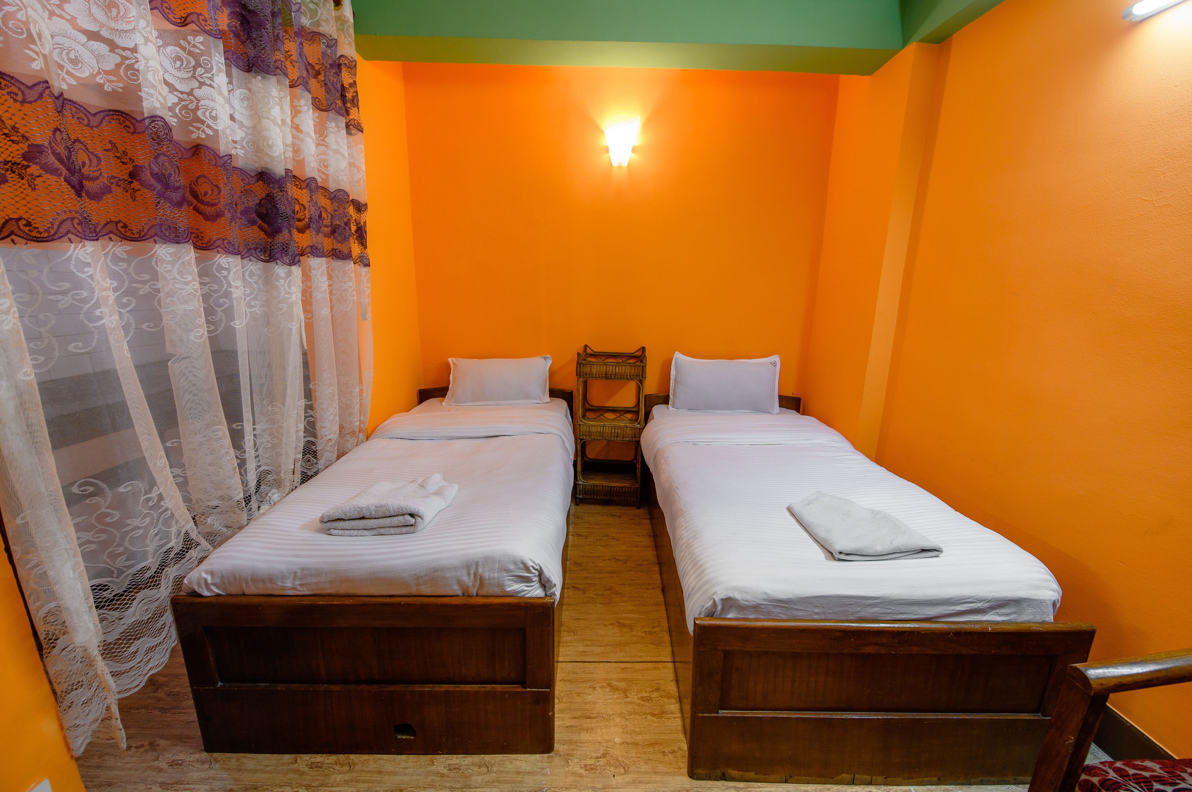 A room with two wooden beds, white linens, and a small wicker chair.