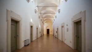 A long, narrow hallway with white walls, multiple doors, and a tiled floor. - Antico Convento San Francesco (Bagnacavallo)