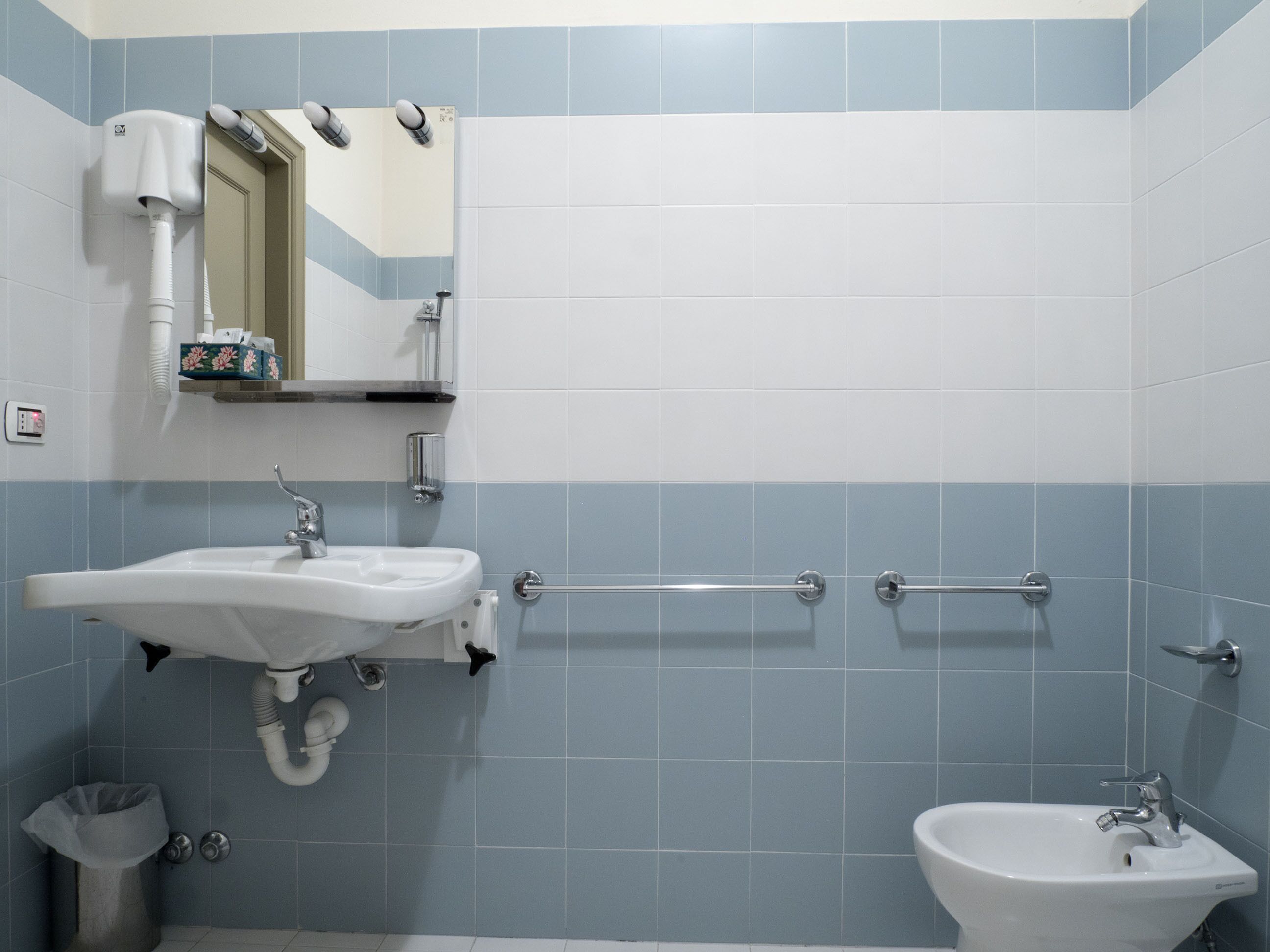 Ein Badezimmer mit Waschbecken, Spiegel und Handtrockner.