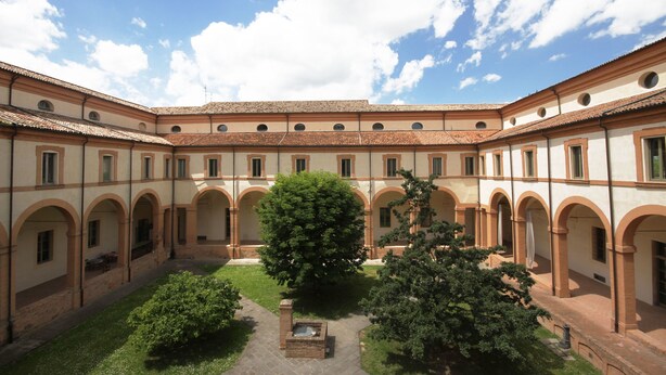 A courtyard with a central tree, surrounded by buildings with arched windows and a tiled roof. - Antico Convento San Francesco (Bagnacavallo)