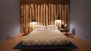 A bedroom with a bed, pillows, a chair, and a wall with wooden planks. - Antico Convento San Francesco (Bagnacavallo)