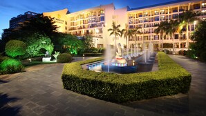 A hotel with a central fountain, landscaped gardens, and multiple balconies. - International Asia-Pacific Convention Center (Sanya)