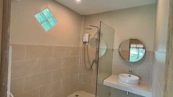 Un baño moderno con cabina de ducha de vidrio, inodoro y lavabo con espejo.