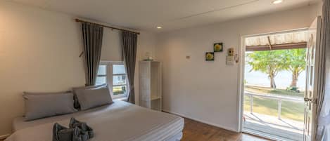 Un dormitorio con cama, cortinas, una ventana, una puerta y vistas al exterior.