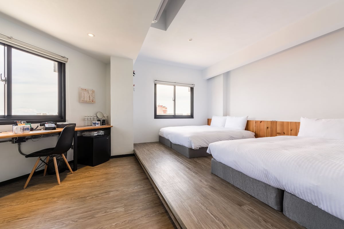 Une chambre d’hôtel avec deux lits, un bureau et une chaise.