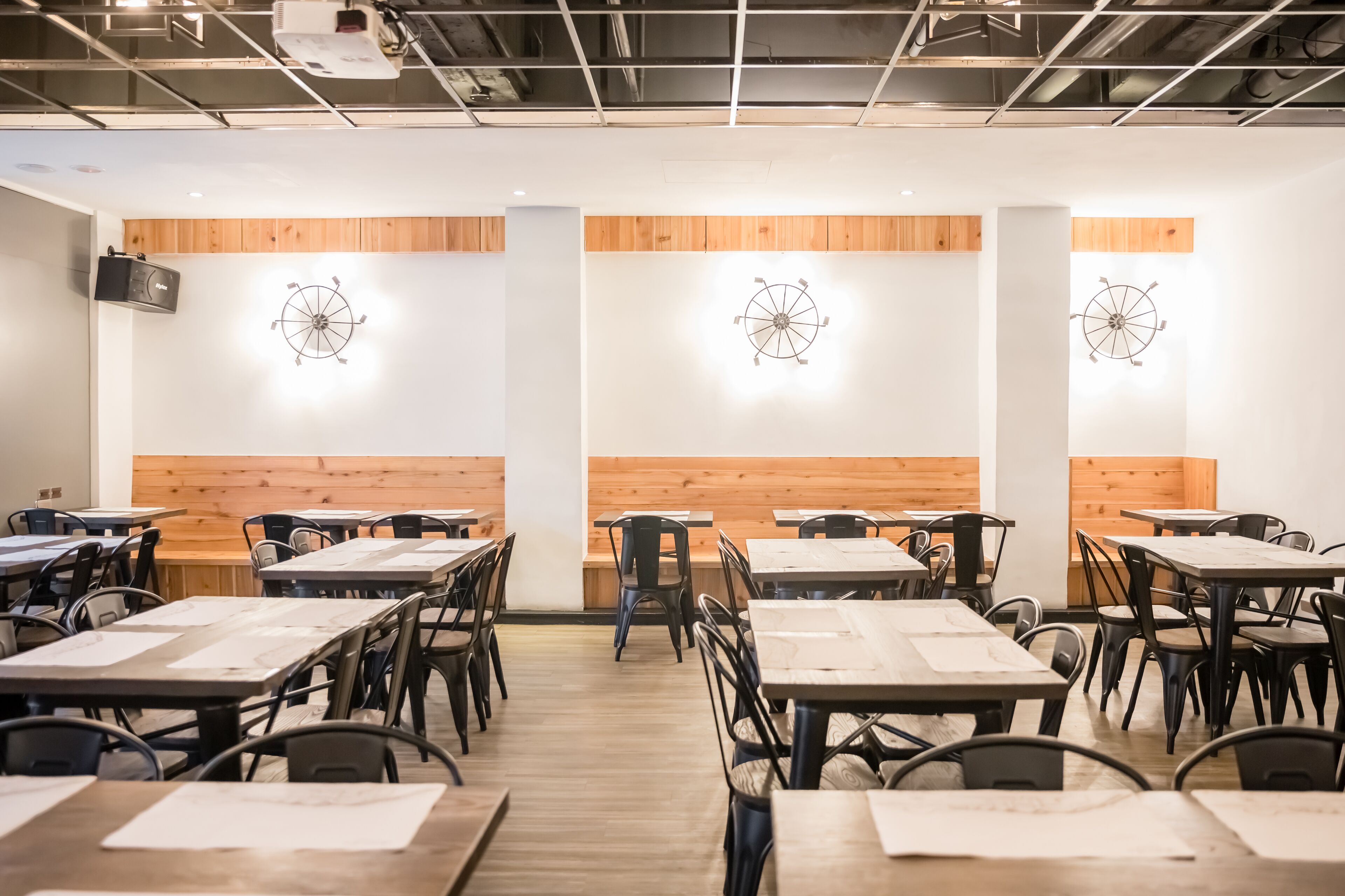 Un espace de restauration moderne avec des murs lambrissés en bois, des chaises et des tables en métal noir.