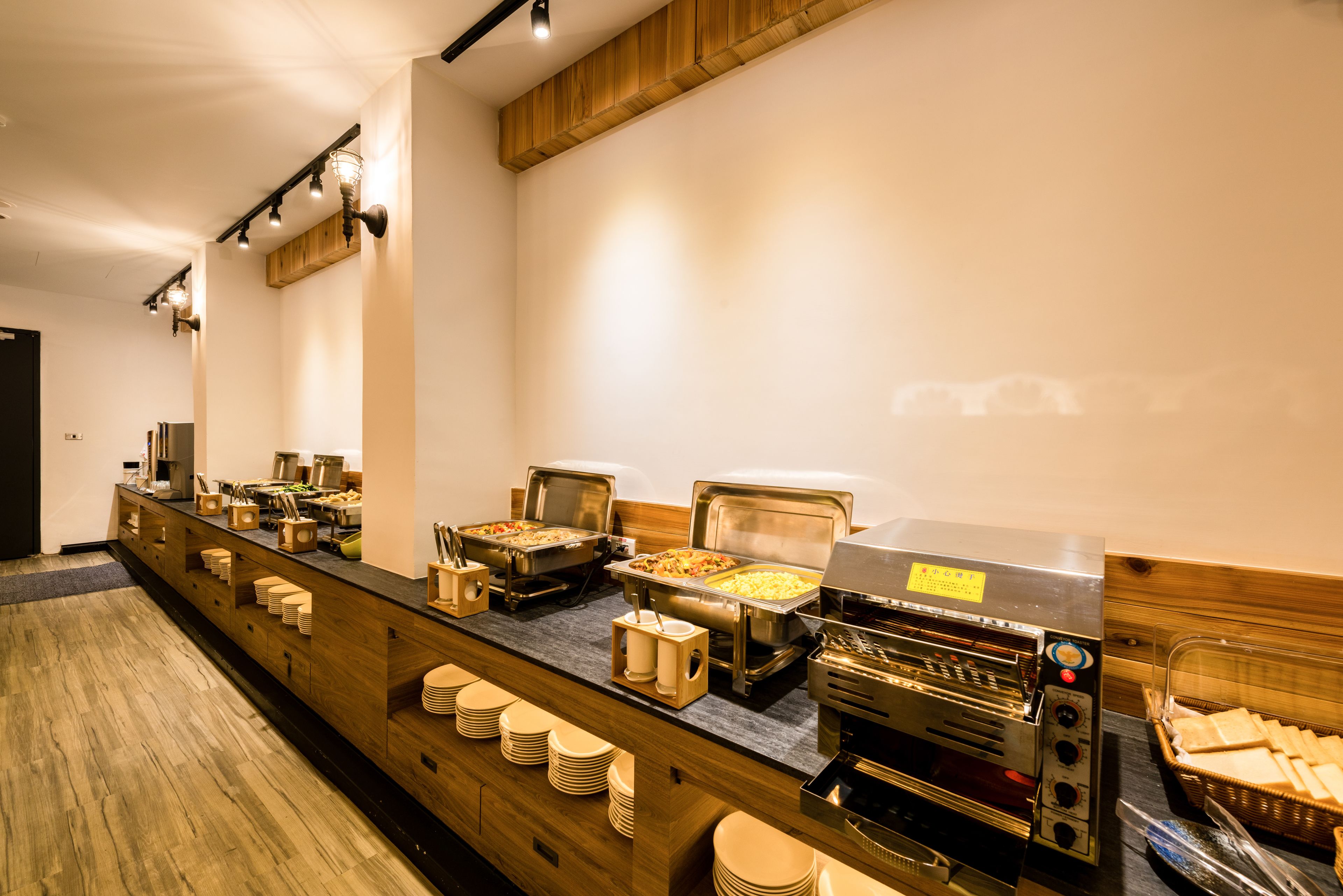 A buffet setup with various food stations, including a hot grill, a salad bar, and a buffet line with stacked plates.