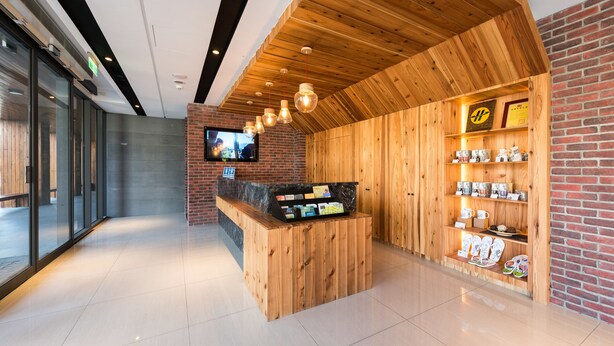 Un espace d’accueil avec un comptoir en bois, un téléviseur fixé au mur et une étagère où sont exposés divers objets.