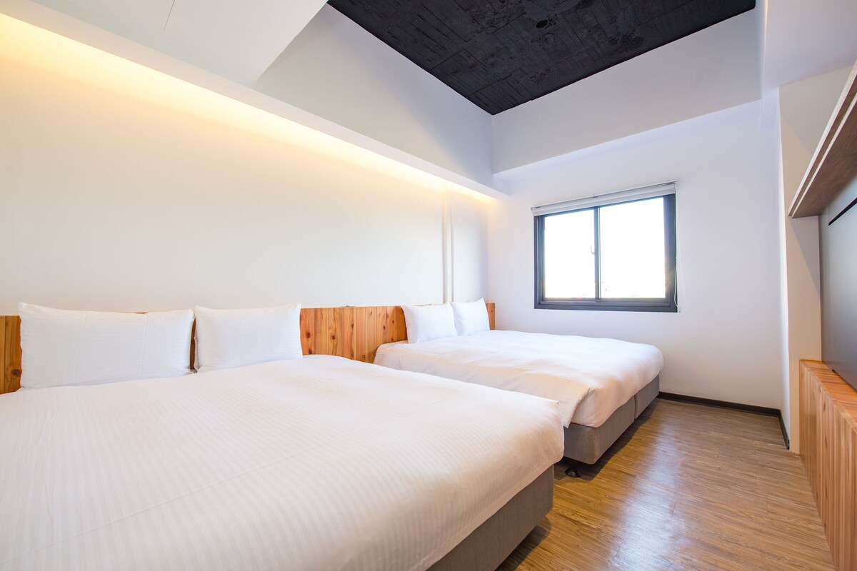 Een hotelkamer met twee bedden, een groot raam en een houten plafond.